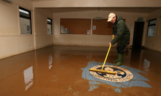 Bill McDonald, of North Angus District Scout Council, fights a losing battle against the flood water at the Jock Neish centre.