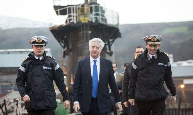 Defence Secretary Michael Fallon (centre) with Commanding Officer of HMS Vigilant Daniel Martyn (left) and Assistant Chief of Naval Staff John Weale (right) during a visit to the Faslane Naval Base on the Clyde.