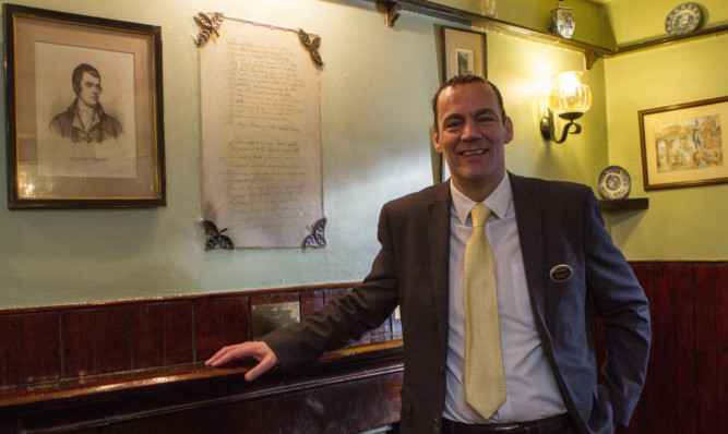 Kenmore Hotel manager Ross McEwan with the framed 
Burns poem on the chimney breast.
