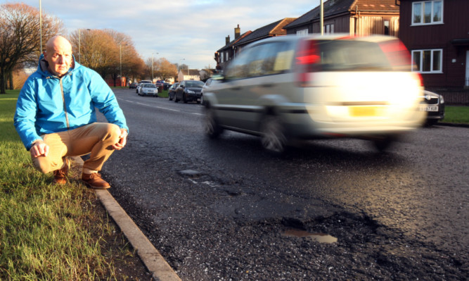 Delivery driver Alex Rossi beside a prominent pothole on Fountainbleau Drive.