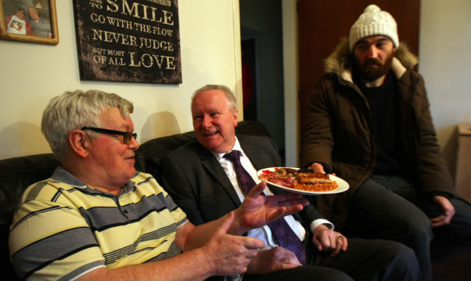 Alex Neil, centre, chats to Patrick Etchels as he is handed a meal by volunteer Paul Boyle.