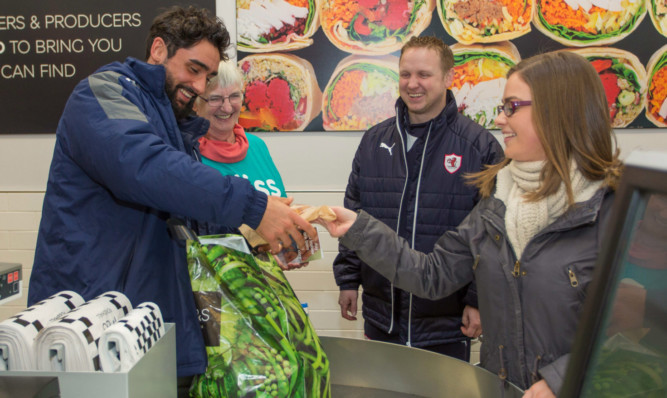 Shopper Jody MacKay has her bags packed by Raith Rovers player Rory McKeown at the new Marks and Spencer food store at the Fife Central Retail Park in Kirkcaldy.