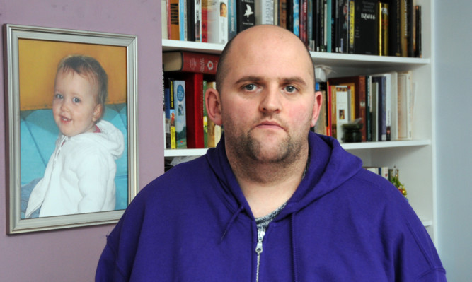 Alan Glynn with a photograph of his daughter who died from meningitis in 2011.