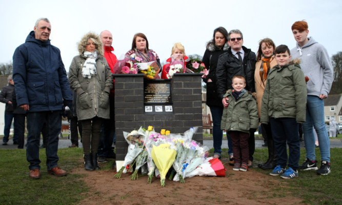 Family of the fishermen gathered around the memorial.