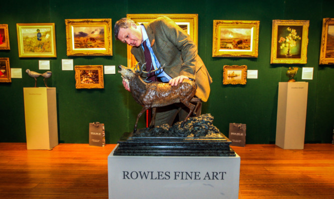 Glenn Rowles of Rowles Fine Art examines a bronze stag sculpture by Julia Wagner, titled Fearless Hart, which has been valued at £19,500.