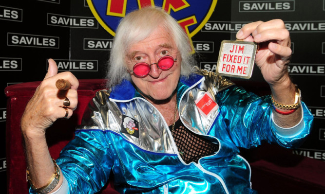 Embargoed to 0001 Tuesday May 19 Sir Jimmy Savile is reunited with his famous Jim'll Fix It chair which is on display at Savile Hall, Leeds.