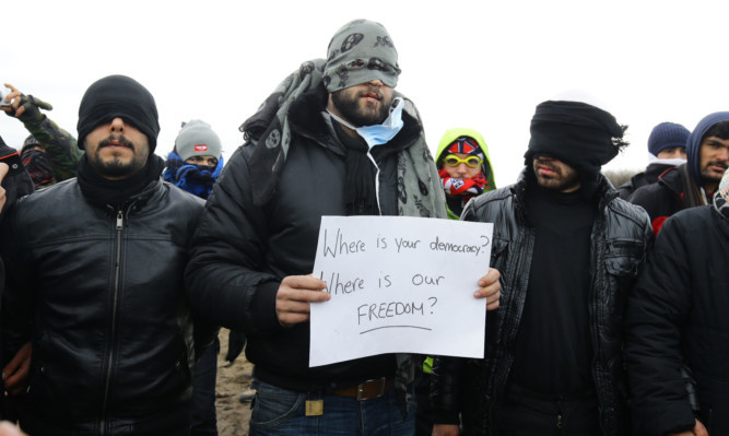 Migrants stage a protest as demolition continues at the Calais migrant camp, known as the Jungle, in northern France.