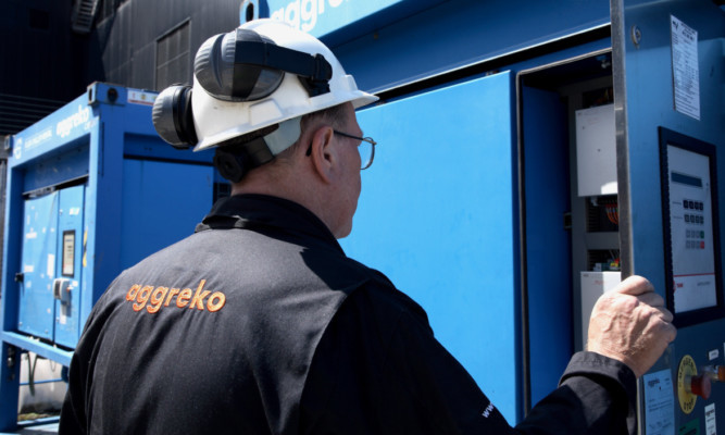 A technician checks over an Aggreko power unit.