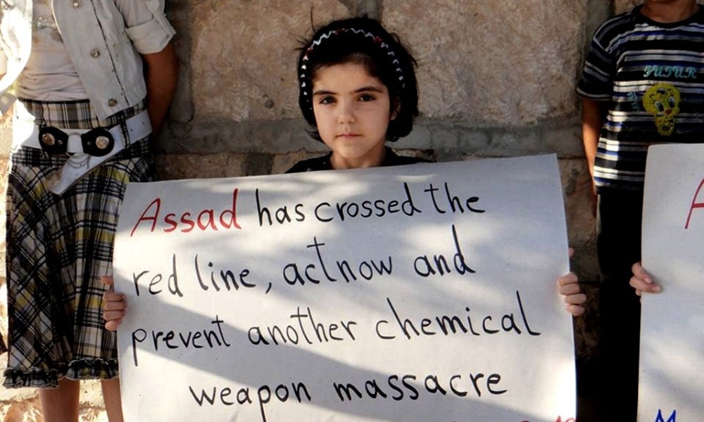 In this Sunday, Sept. 1, 2013, citizen journalism image provided by Edlib News Network, ENN, which has been authenticated based on its contents and other AP reporting, a Syrian girl holds a sign during a demonstration in Maaret al-Numan, Idlib province, northern Syria. More than 100,000 Syrians have been killed since an uprising against Syrian President Bashar Assad erupted in 2011. (AP Photo/Edlib News Network ENN)