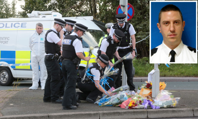 Police officers lay floral tributes at the scene in Wallasey North Road, Wallasey, Merseyside, where Pc David Phillips (inset) was mown down and killed by a stolen car.