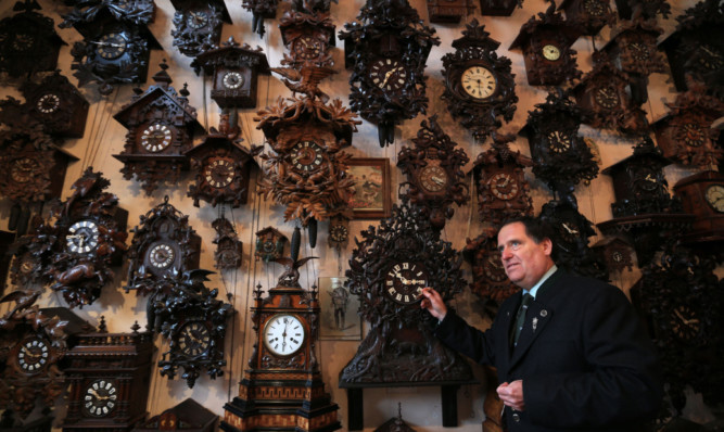 Horologist Roman Piekarski has a wall of antique clocks to change at Cuckooland Museum in Tabley.