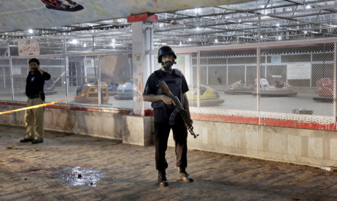 Pakistani police officers stand guard at the site of a bomb blast in a park in Lahore, Pakistan.