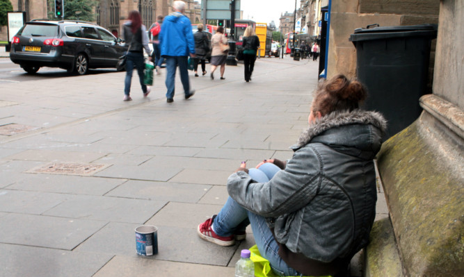 A woman begs for money from passersby in the centre of Dundee.