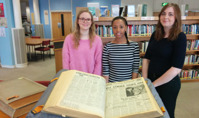 Students Mhairi Anderson, Nesha Dixon an Amy Morrison trawl through an old newspaper for clues.