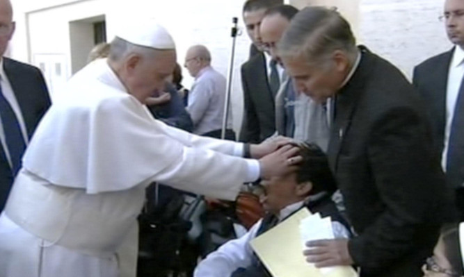 Pope Francis lays his hands on the head of a young man on Sunday, an act some people think was an exorcism.