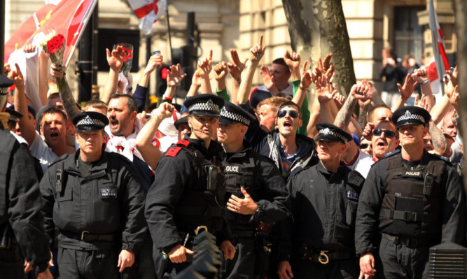 Police officers stand in front of EDL demonstrators on Whitehall.