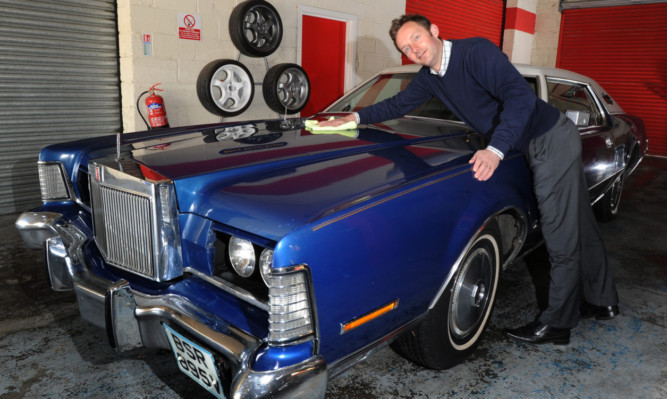 Auctioneer Steven Dewar puts a shine on the 1973 Lincoln Continental.