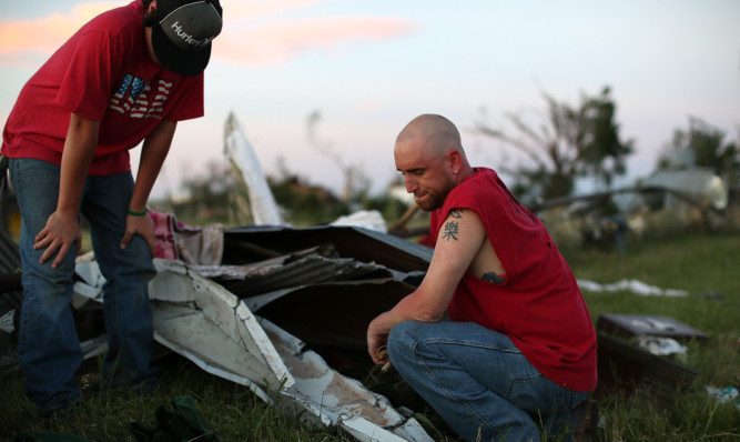 Locals pause while looking through debris after a series of tornadoes ripped through El Reno, Oklahoma.
