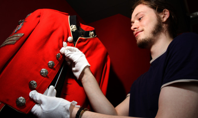 Mount maker and designer James Wheeler removing protective coverings on a 4th Battalion Royal Highland Volunteers' jacket.