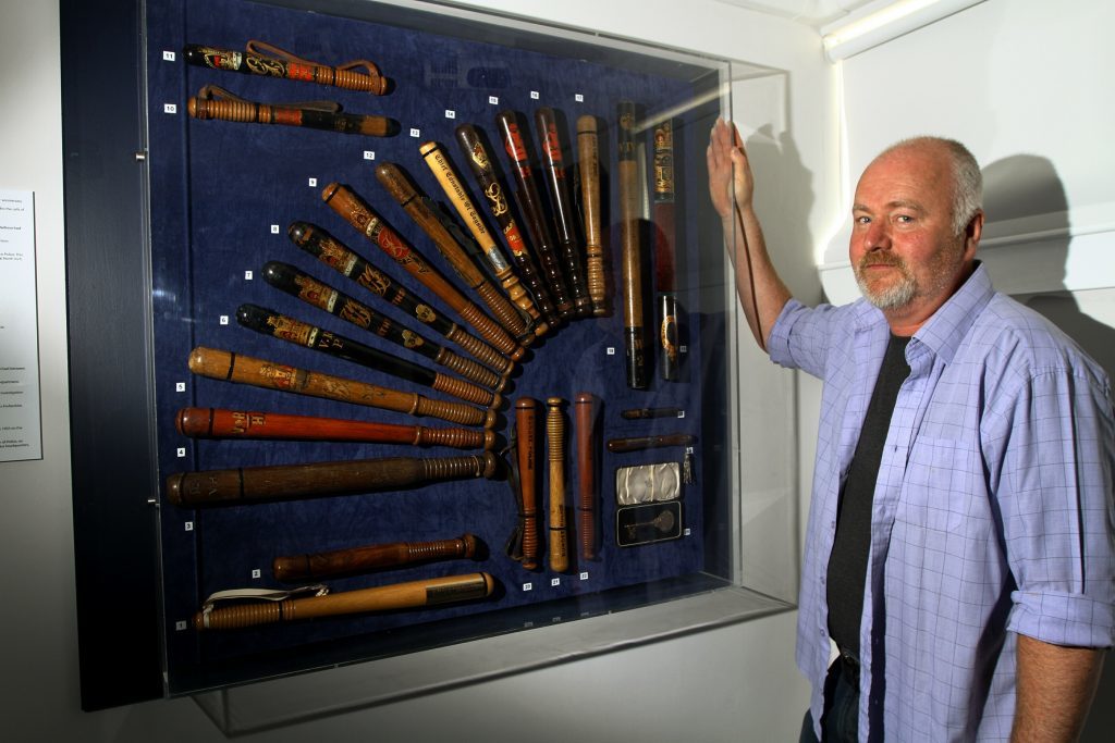 Retired Inspector Hamish Gray, beside a collection of police truncheons.