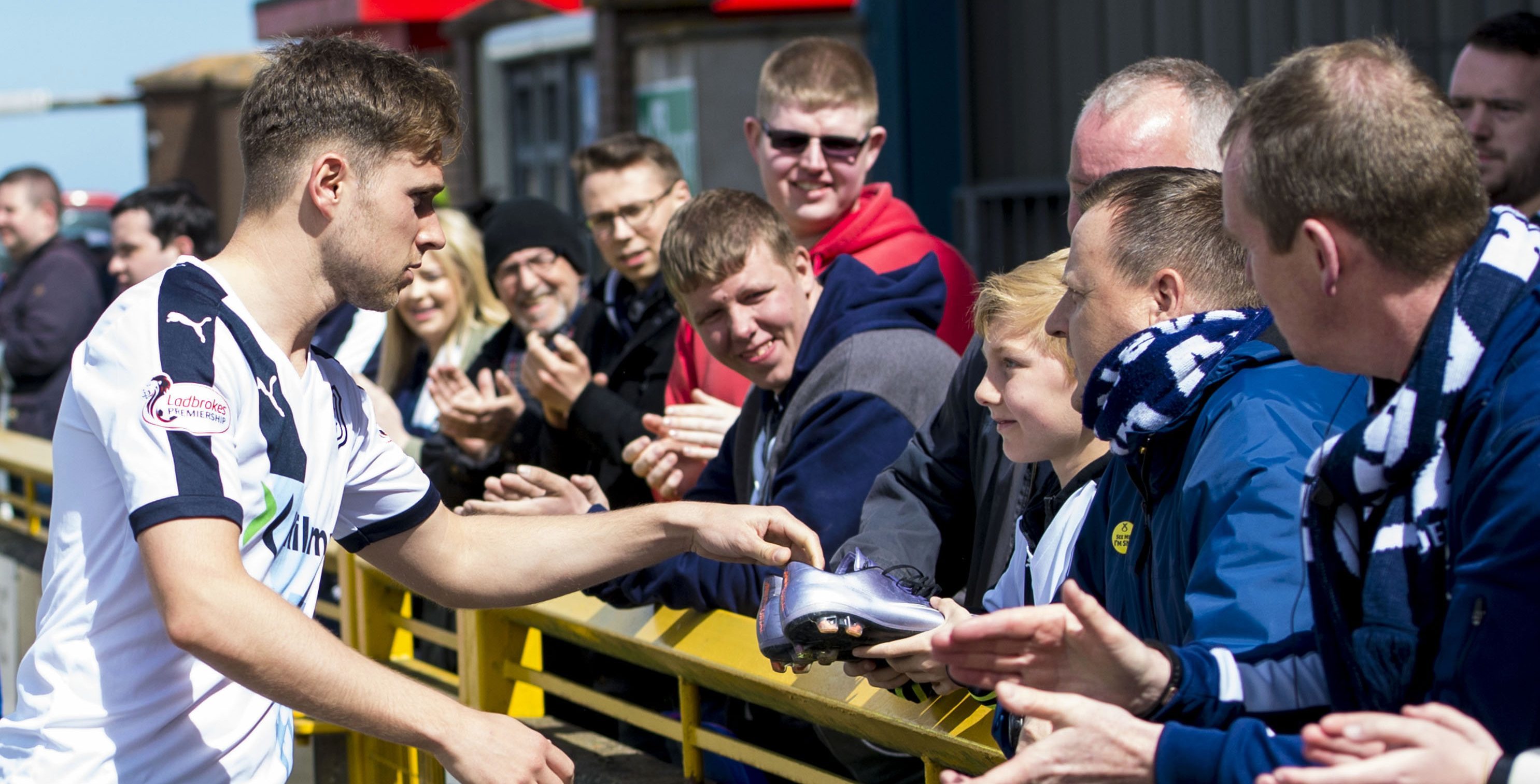 Greg Stewart giving his boots to a Dundee fan at the end of their last game of the season at Inverness on Saturday.