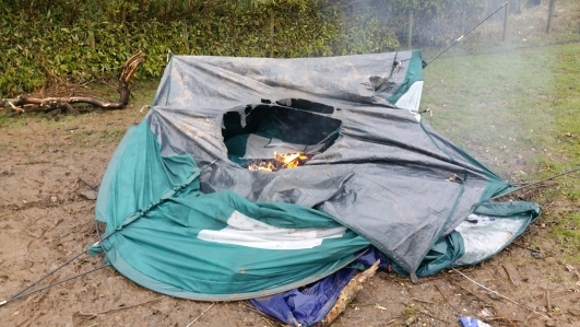A tent abandoned and set on fire.