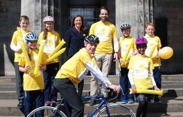 Mark pictured outside the High School of Dundee, with pupils from the school and Marie Curie patron Petra McMillan.