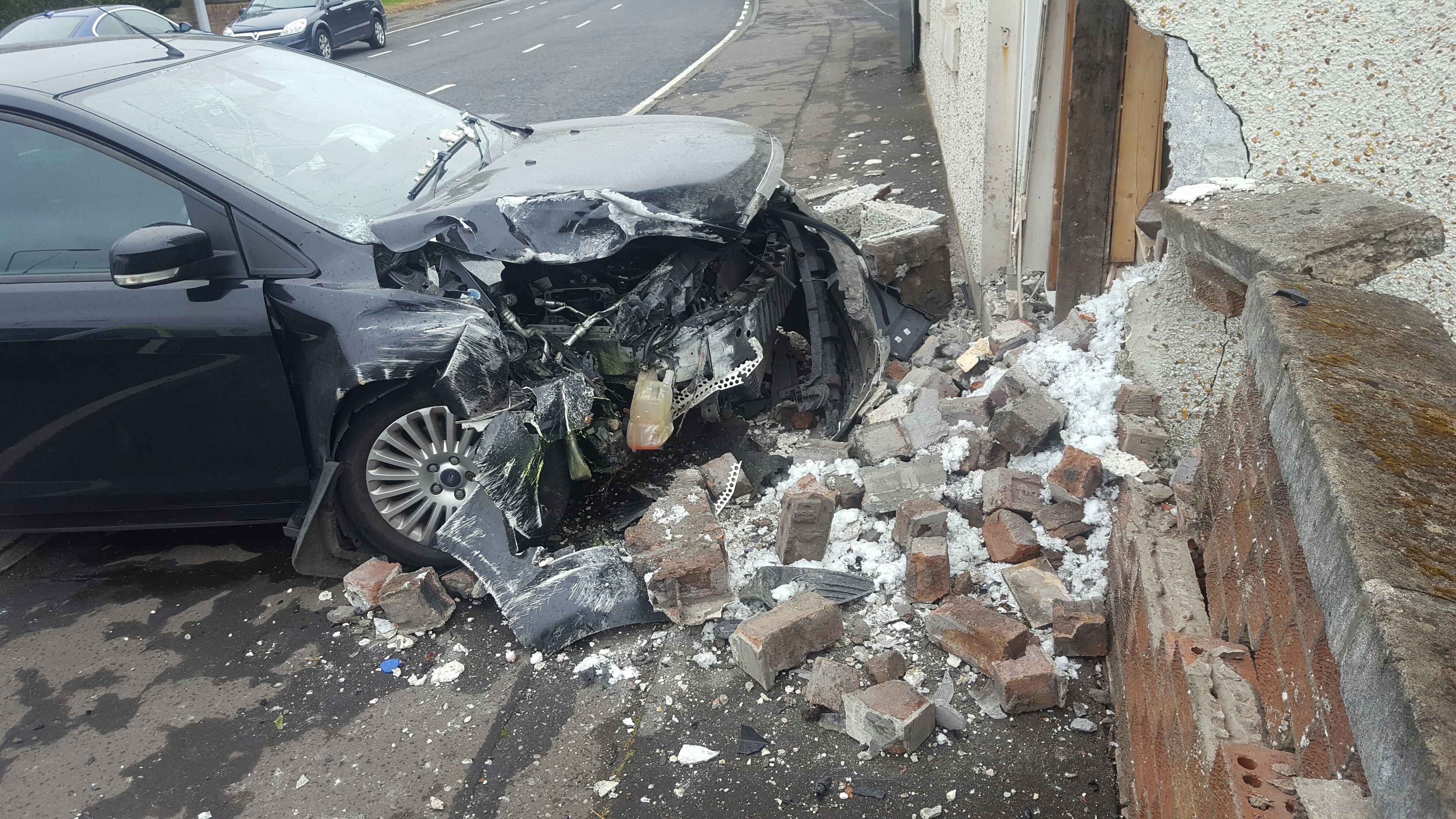 The badly damaged car lies amid the rubble after the impact.