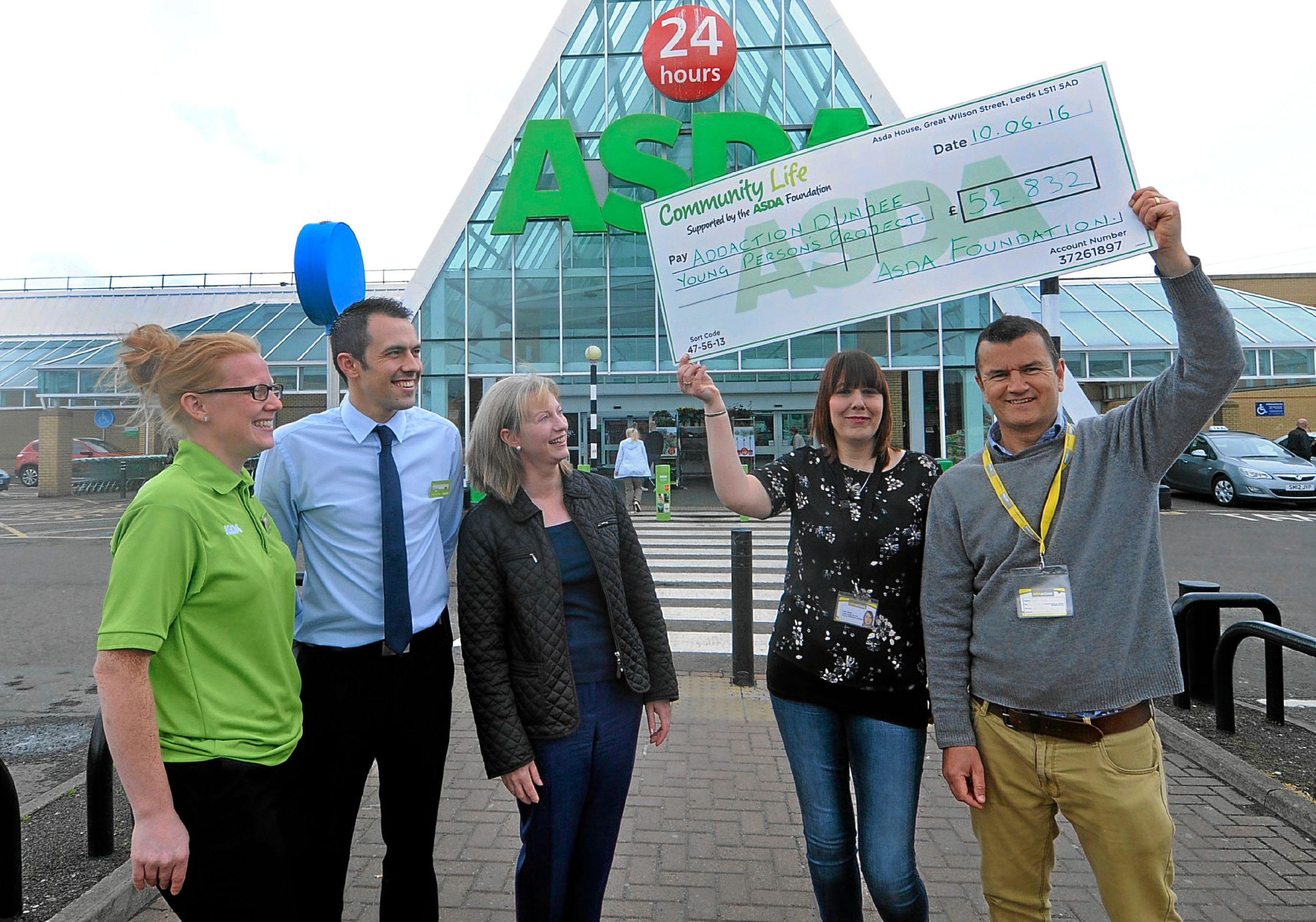 Asda's Yvanne McLaren and Craig Fisher and MSP Shona Robison look on as Alain Saum and Dave Barry of Young Addaction, Dundee hold up the cheque.