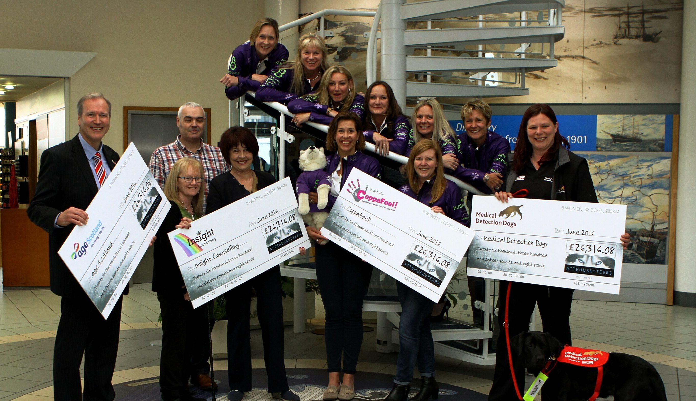 The Huskyteers hand their cheques to four charities