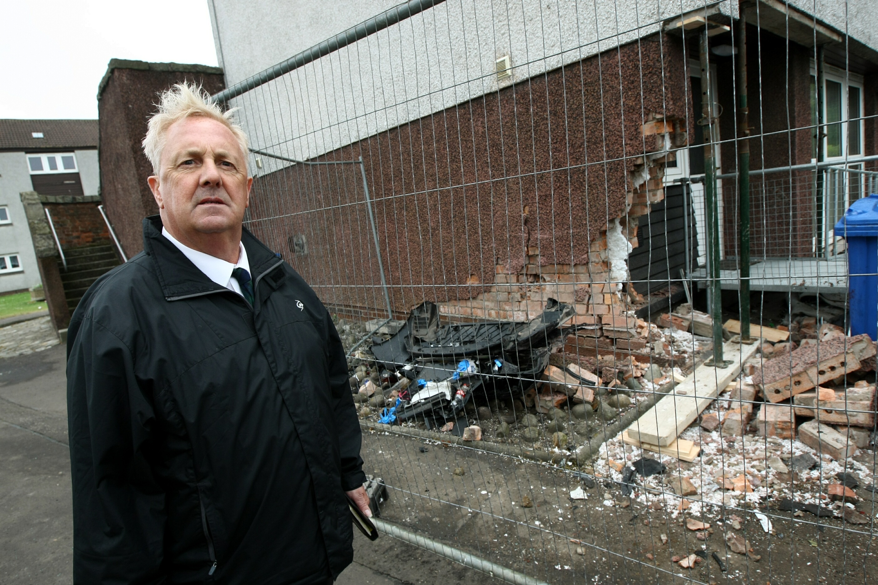 Councillor John O'Brien surveys damage to flats after a car crash in Methil.