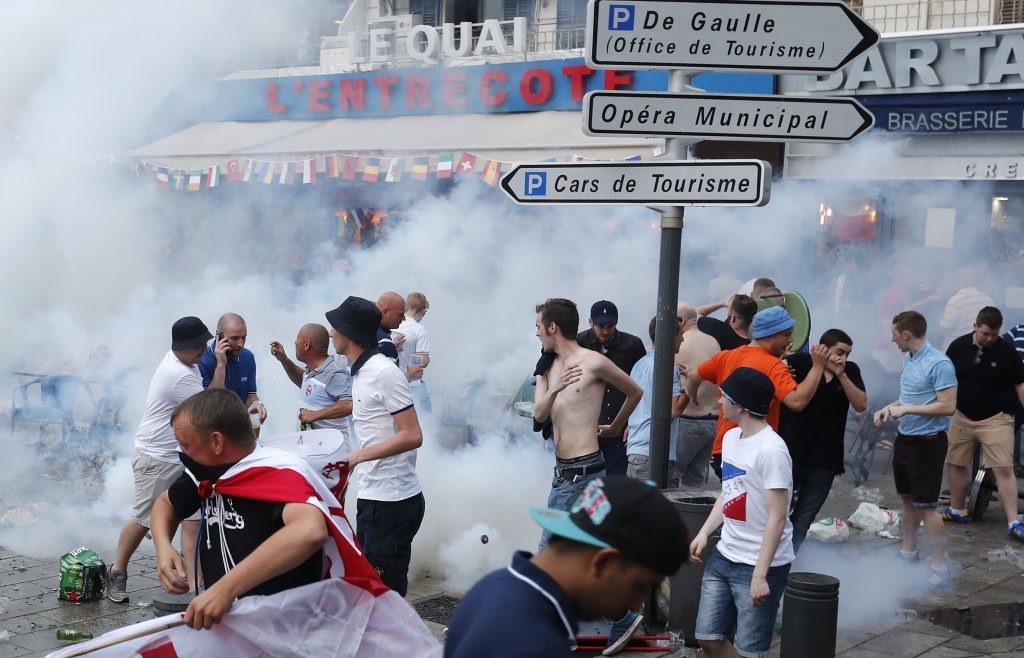 England supporters take evasive action after French police fired tear gas at them in downtown Marseille, France, Friday, June 10, 2016. Some minor scuffles on Friday and the brief clashes late Thursday revived bitter memories of days of bloody fighting in this Mediterranean port city between England hooligans, Tunisia fans and locals of North African origin during the World Cup in 1998, and raised fears of more violence ahead of Saturday's European Championship match between England and Russia at the Stade Velodrome.(AP Photo/Darko Bandic)