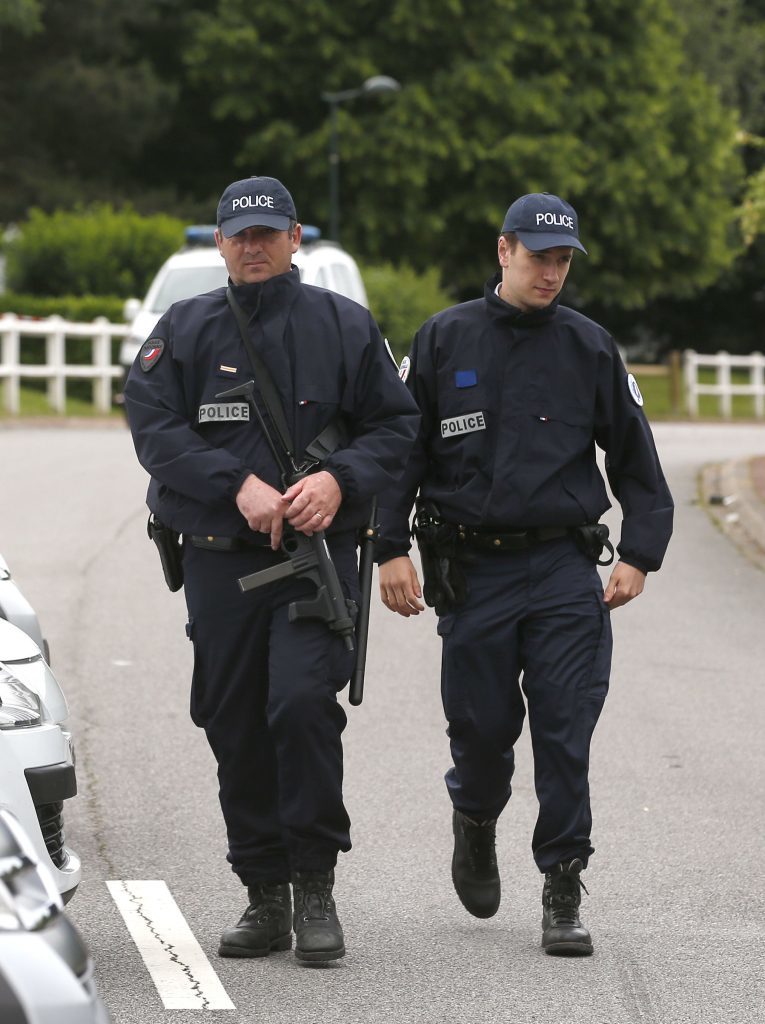 French police officers block the road leading to a crime scene the day after a knife-wielding attacker stabbed a senior police officer to death Monday evening outside his home in Magnanville, west of Paris, France, Tuesday, June 14, 2016. The attacker and a female companion of the police commander were later found dead after police commandos stormed the home and rescued the couple's three-year-old son. (AP Photo/Thibault Camus)