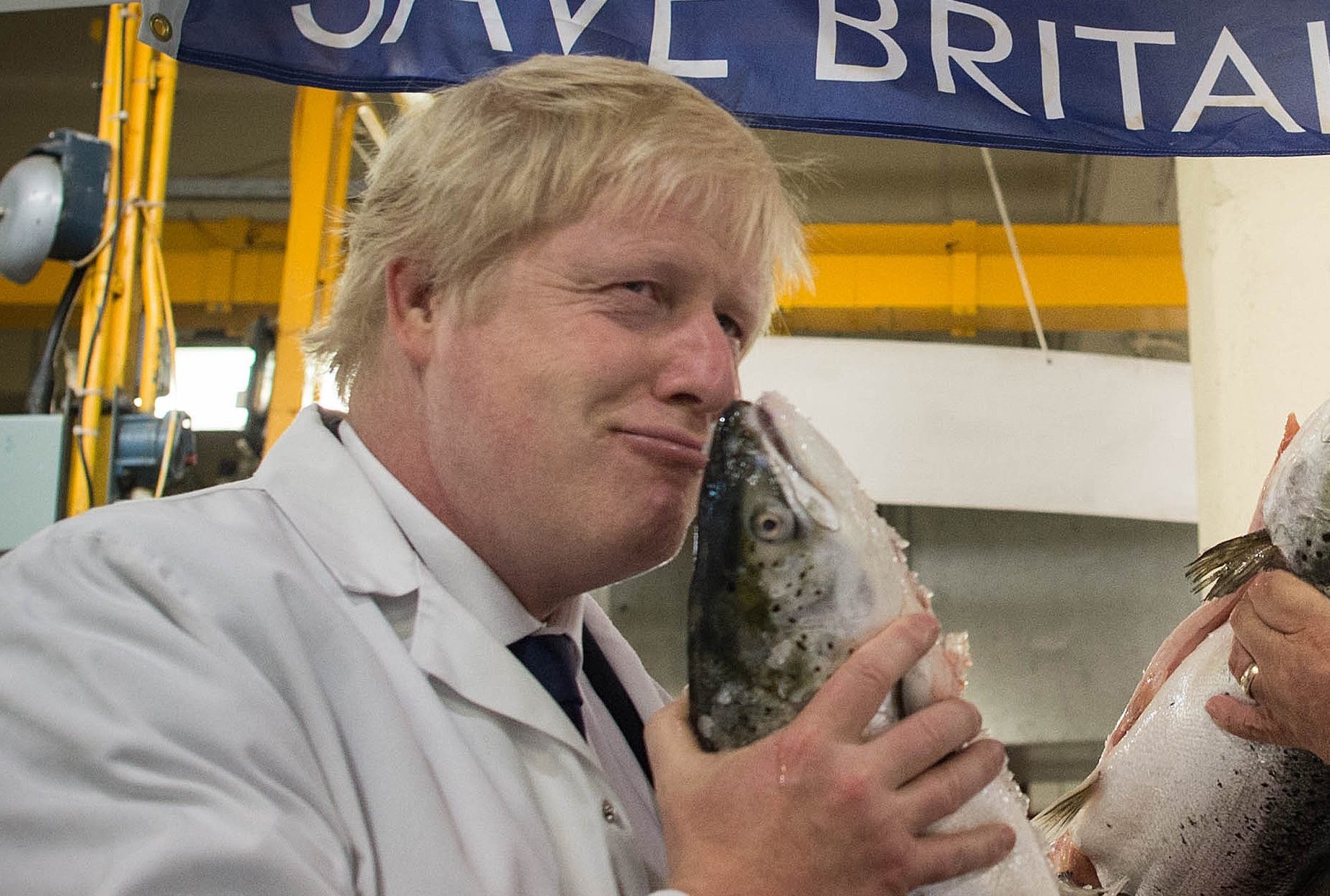Boris Johnson (left) kisses a wild salmon as he is shown around Billingsgate Fish Market in London with porter Greg Essex on Wednesday morning