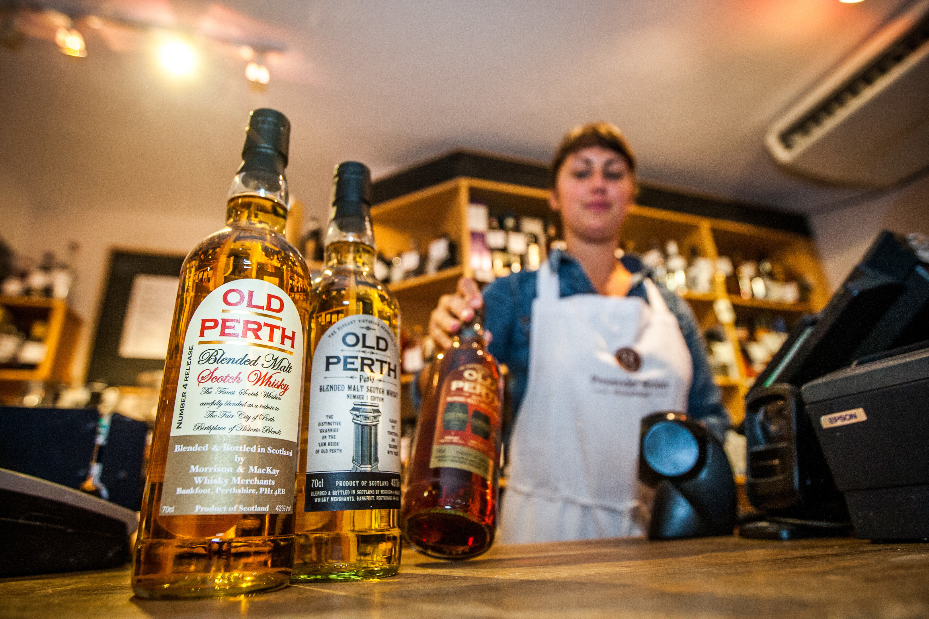 A staff member at the Provender Brown delicatessen on George Street stocking the alcohol shelves in the shop.