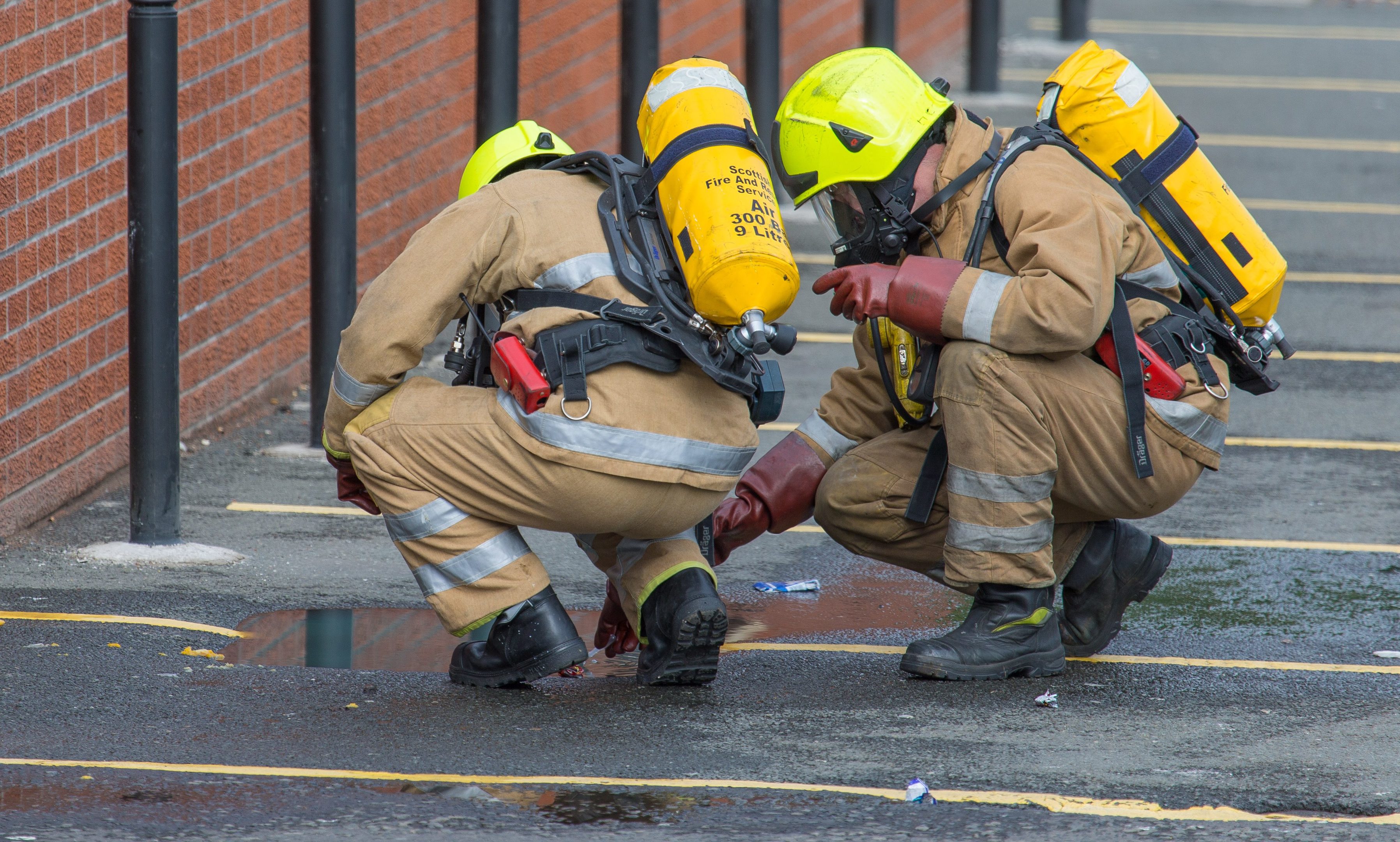 Firefighters wearing breathing apparatus take samples from the water.