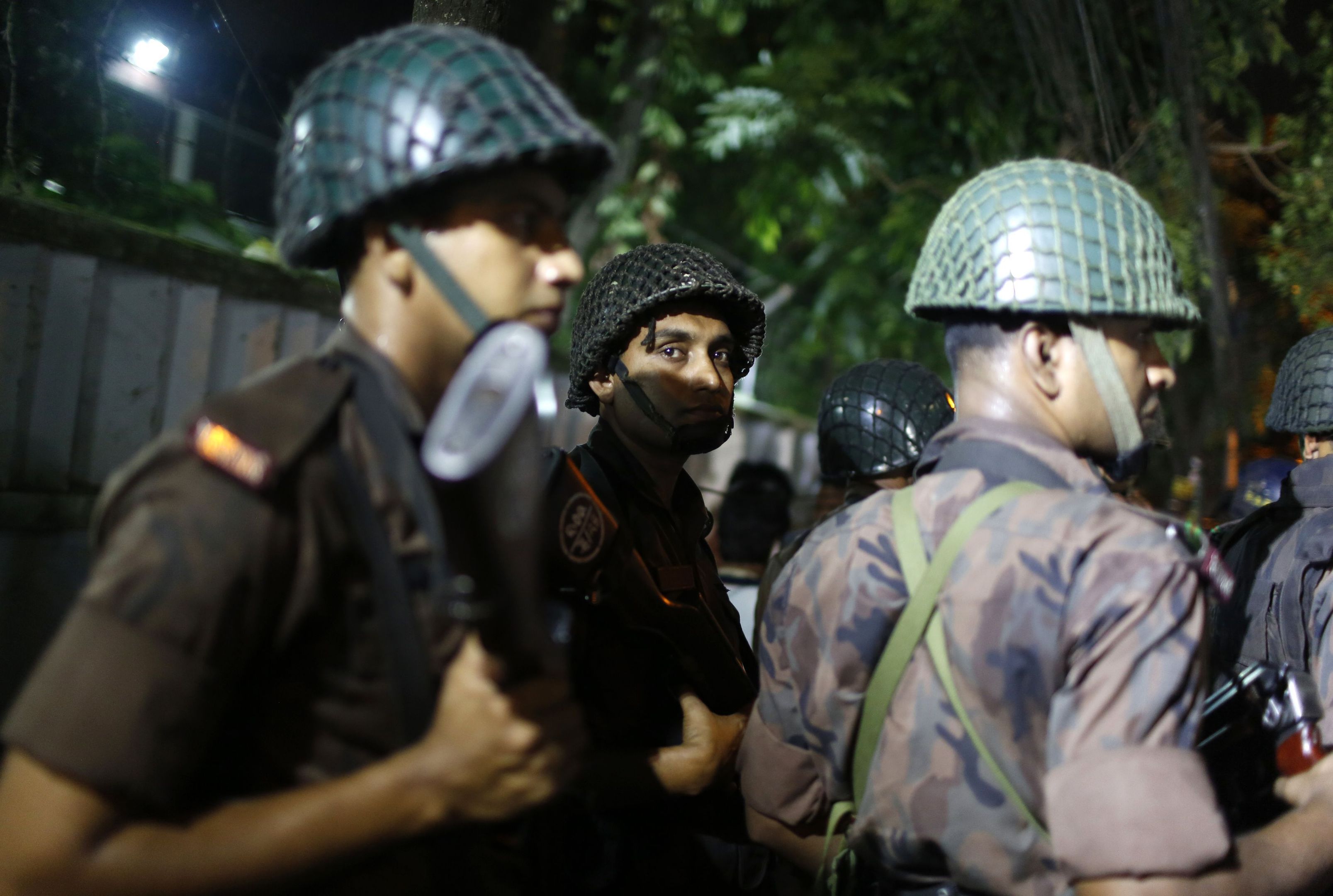 Bangladeshi security personnel stand guard near a restaurant that has reportedly been attacked by unidentified gunmen in Dhaka.