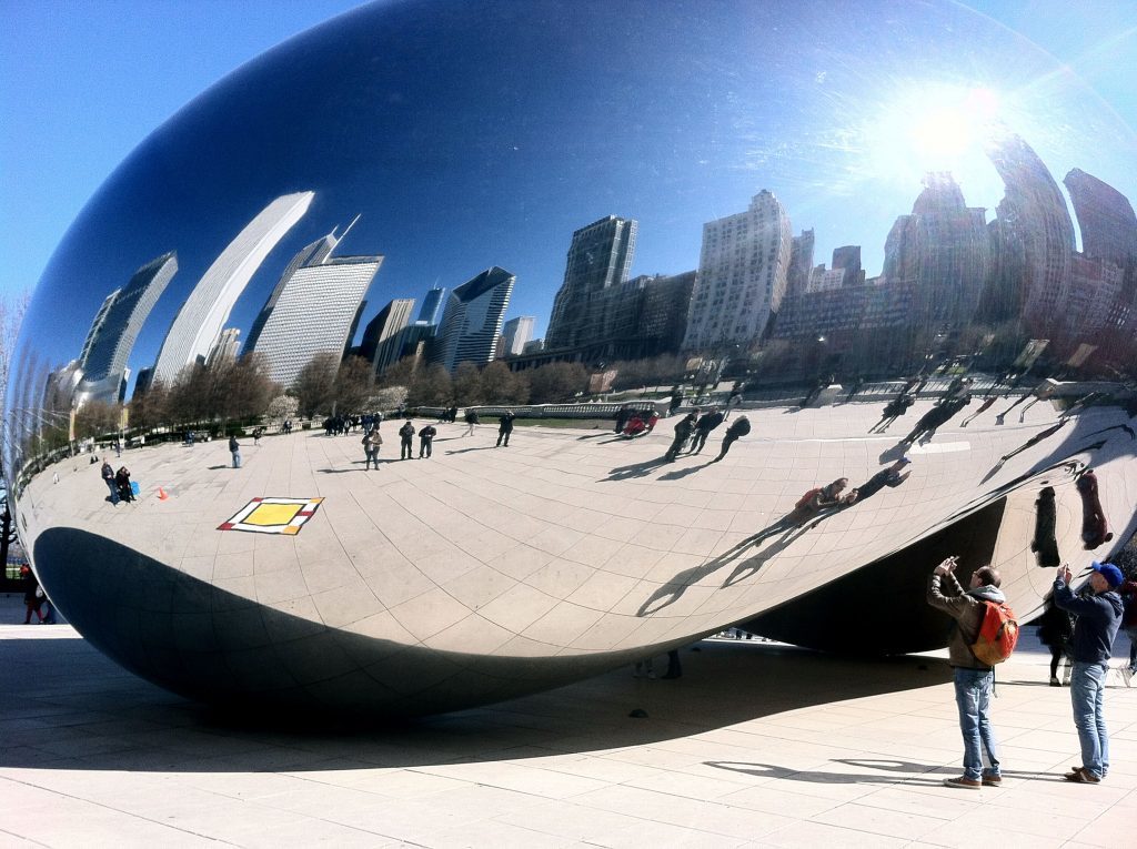Photo of the skyline of Chicago including the Chicago Athletic Association Hotel reflected in the surface of Anish Kapoor sculpture Cloud Gate in Millennium Park.