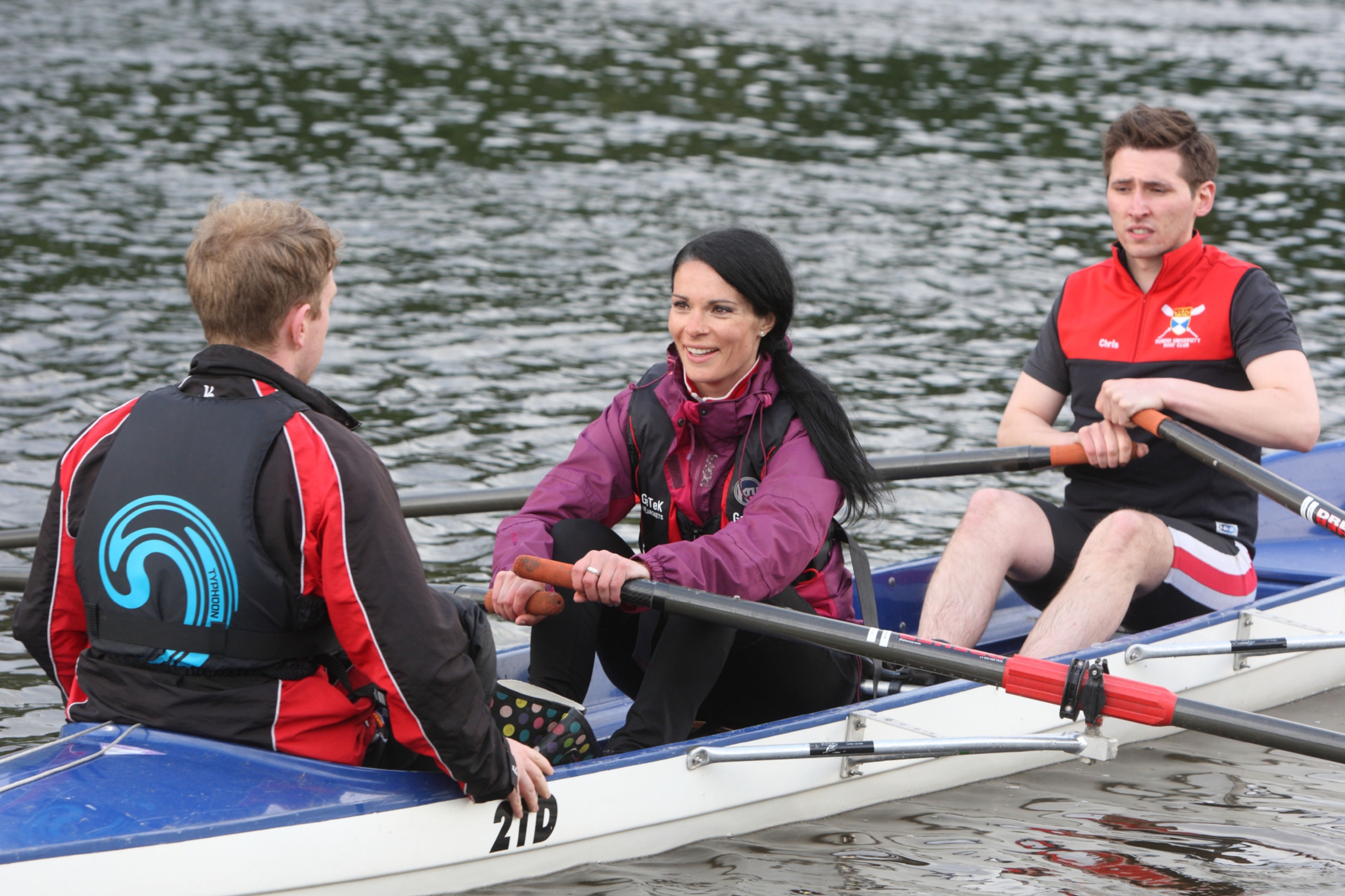 Eoin Ryan (L) and Chris Bell (R) show Gayle Ritchie how to row.