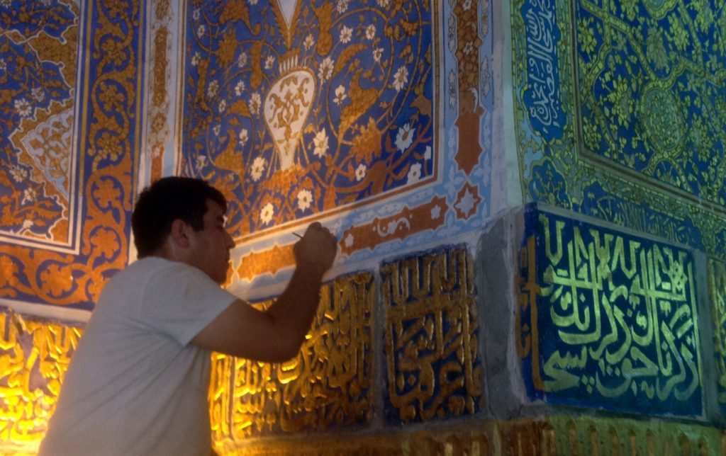 Photo of a a man repainting the inside of the Registan. 