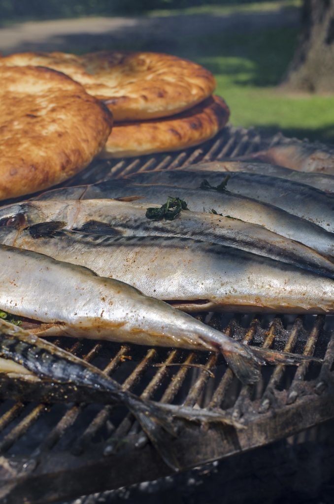 Sea fish (scomber, mackerel) on grill with flatbread on background