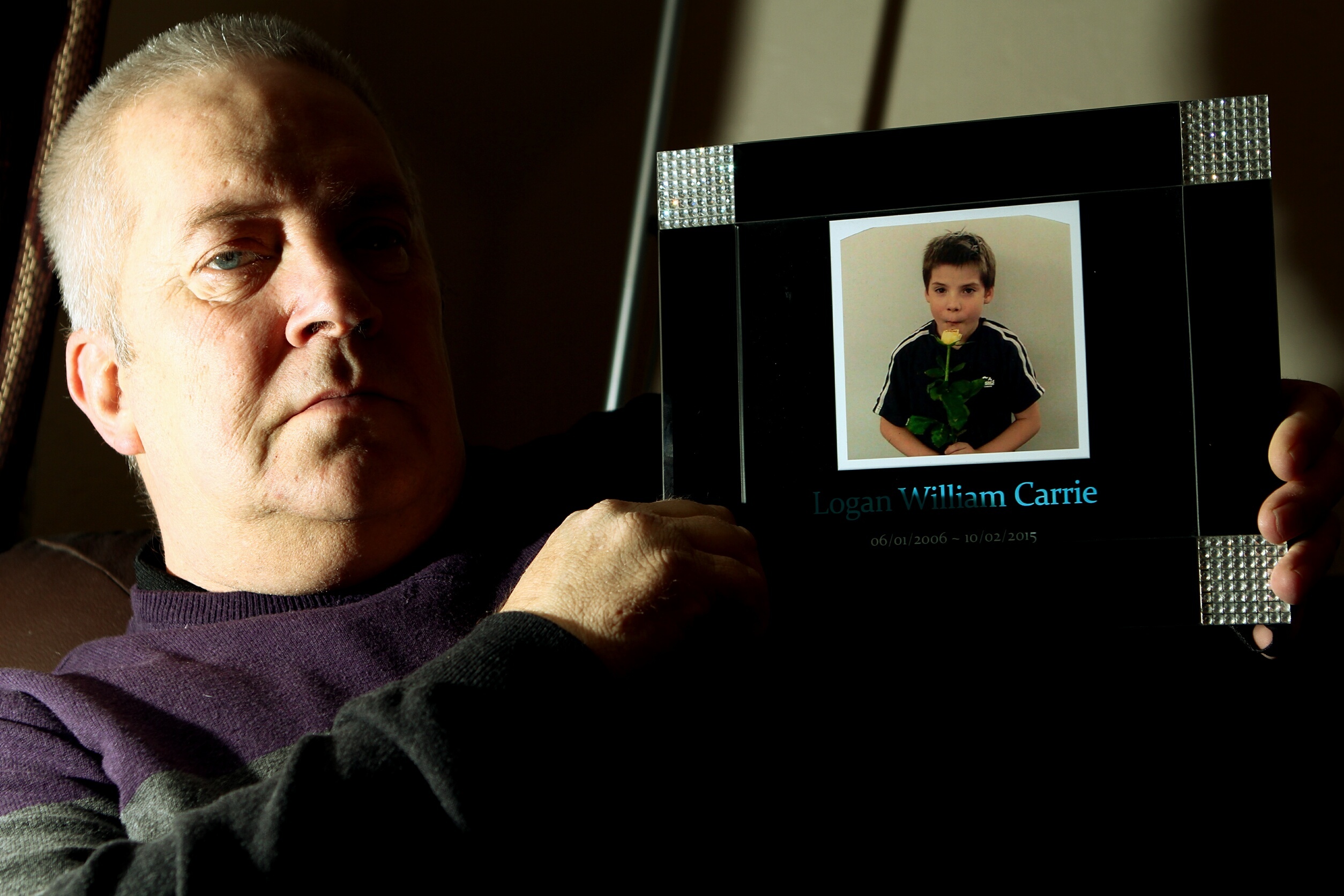 Robert Brown holding a photo of his late grandson Logan Carrie.