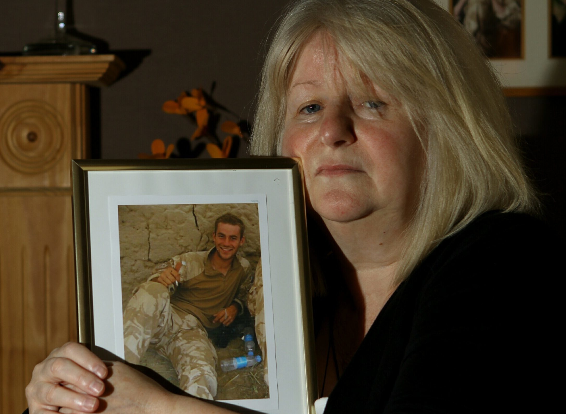 June Black with a photograph of her late son Aaron who committed suicide seven months after coming out of the army