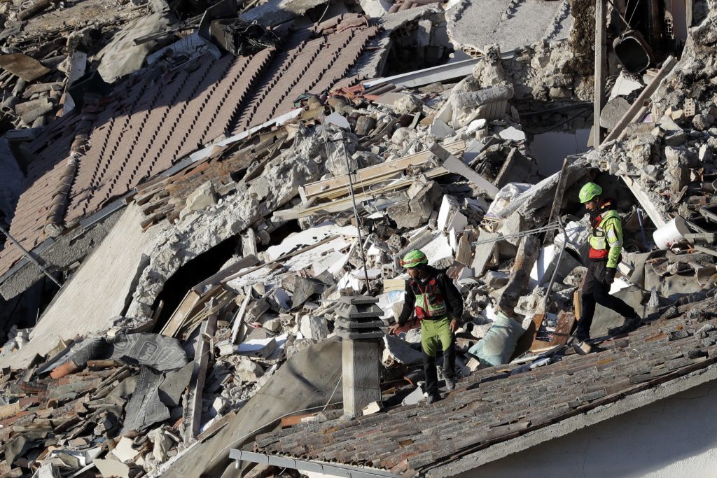 Rescuers make their way through destroyed houses in Pescara Del Tronto.