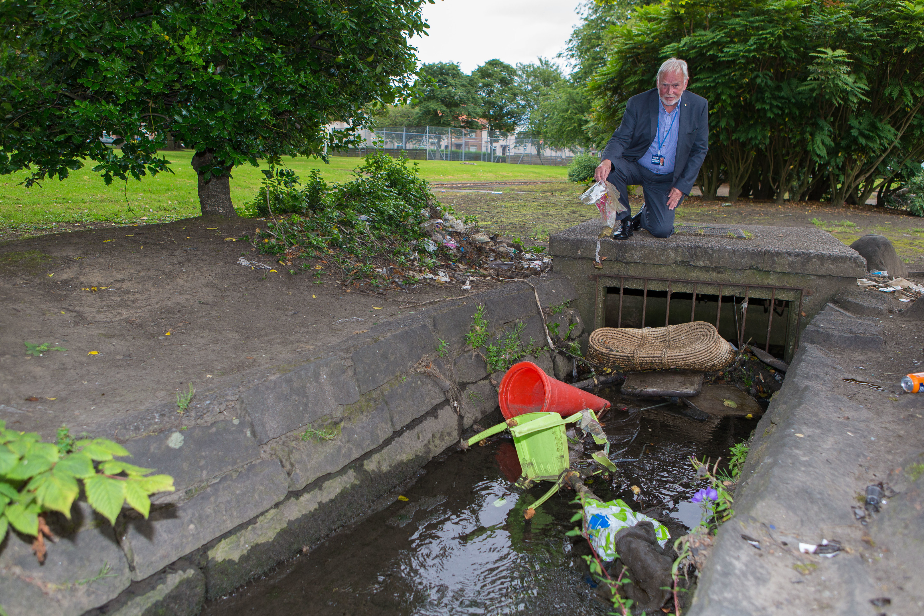 Councillor Stuart MacPhail surveying the rubbish in the burn at Adamson Avenue.