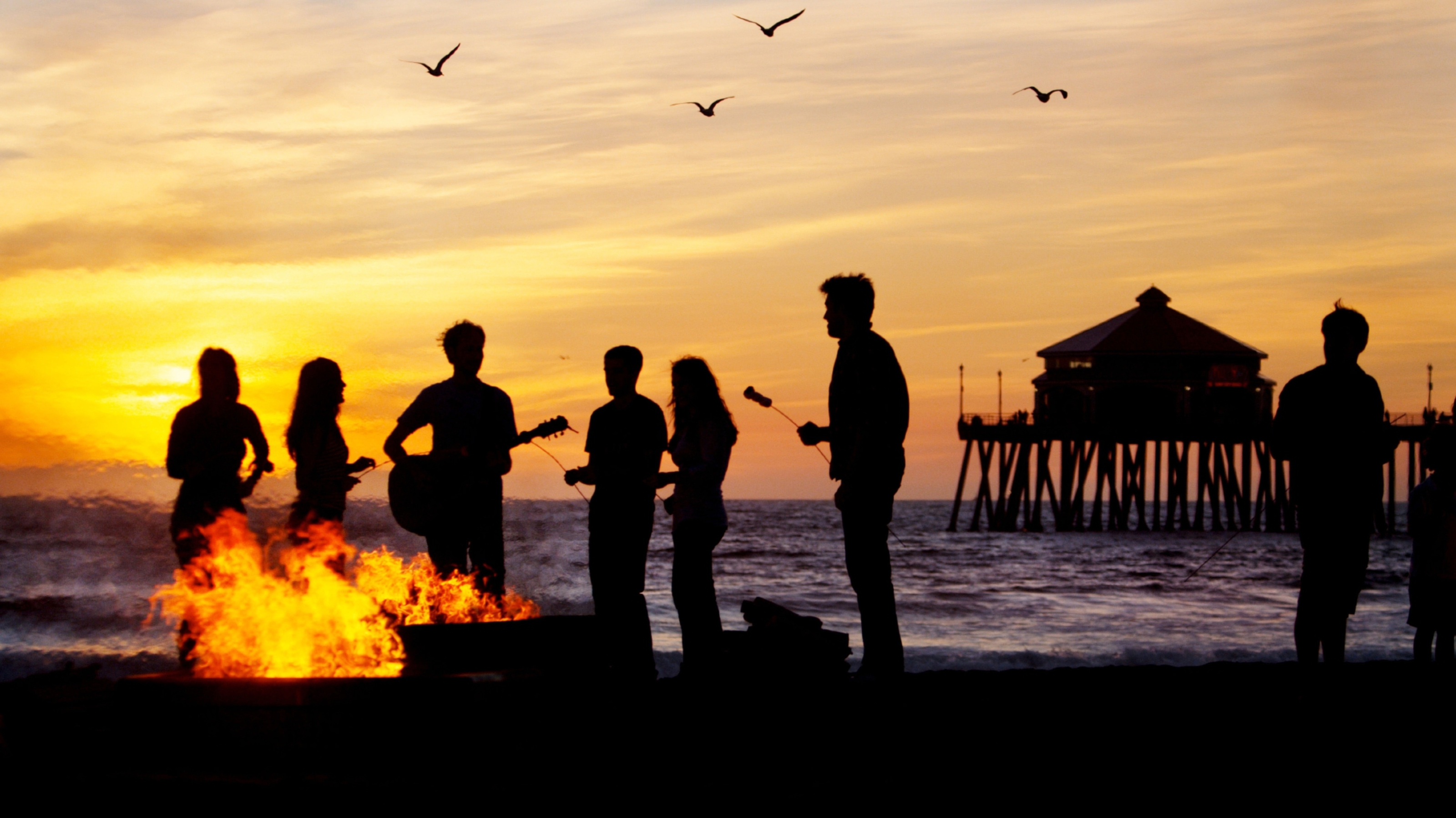 The sun setting as people have a bonfire on Huntington Beach.