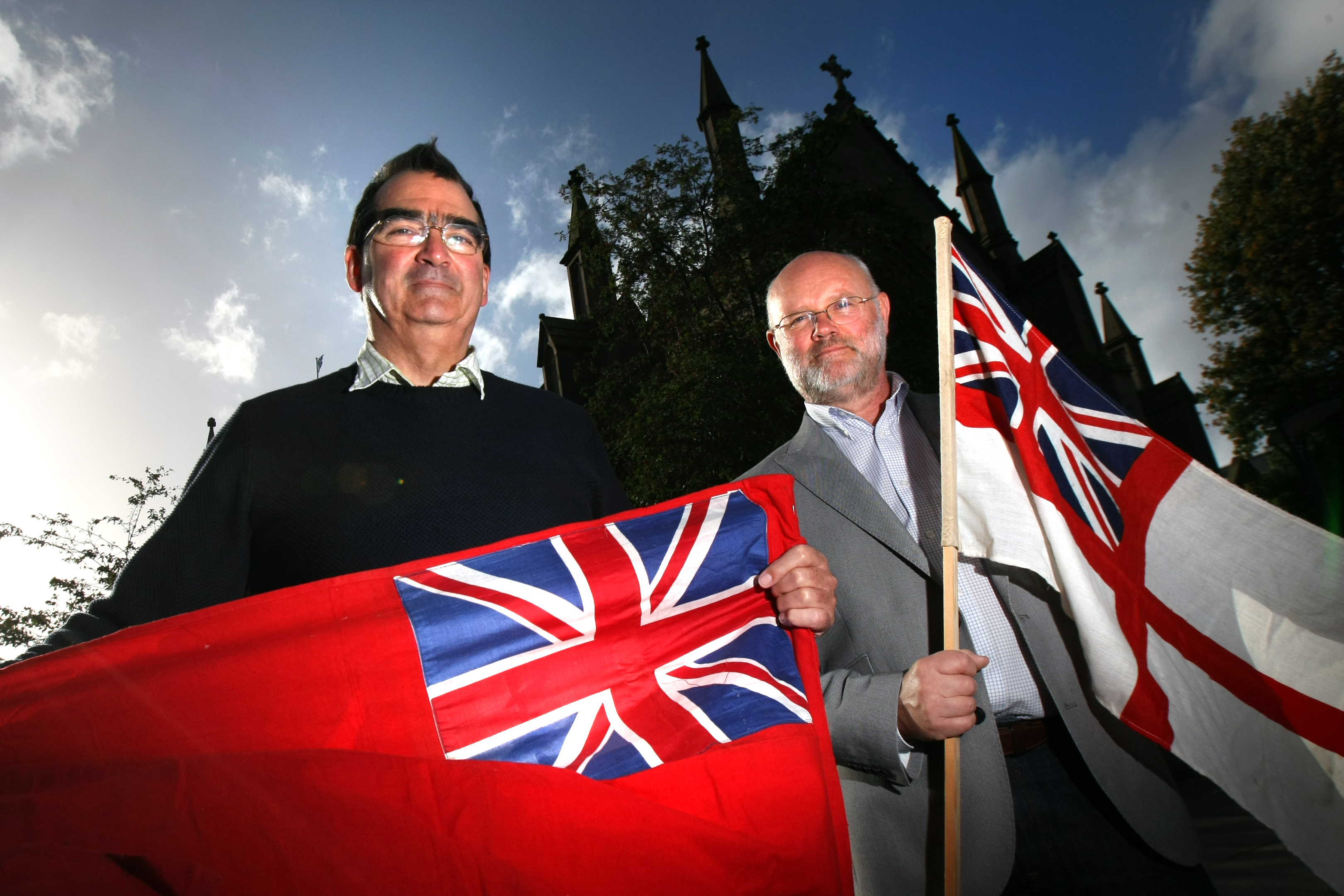Historian Hugh Macrae and Lt Cmd Iain Stewart with the Merchant and Royal Navy flags outside St Mary's Parish Church.