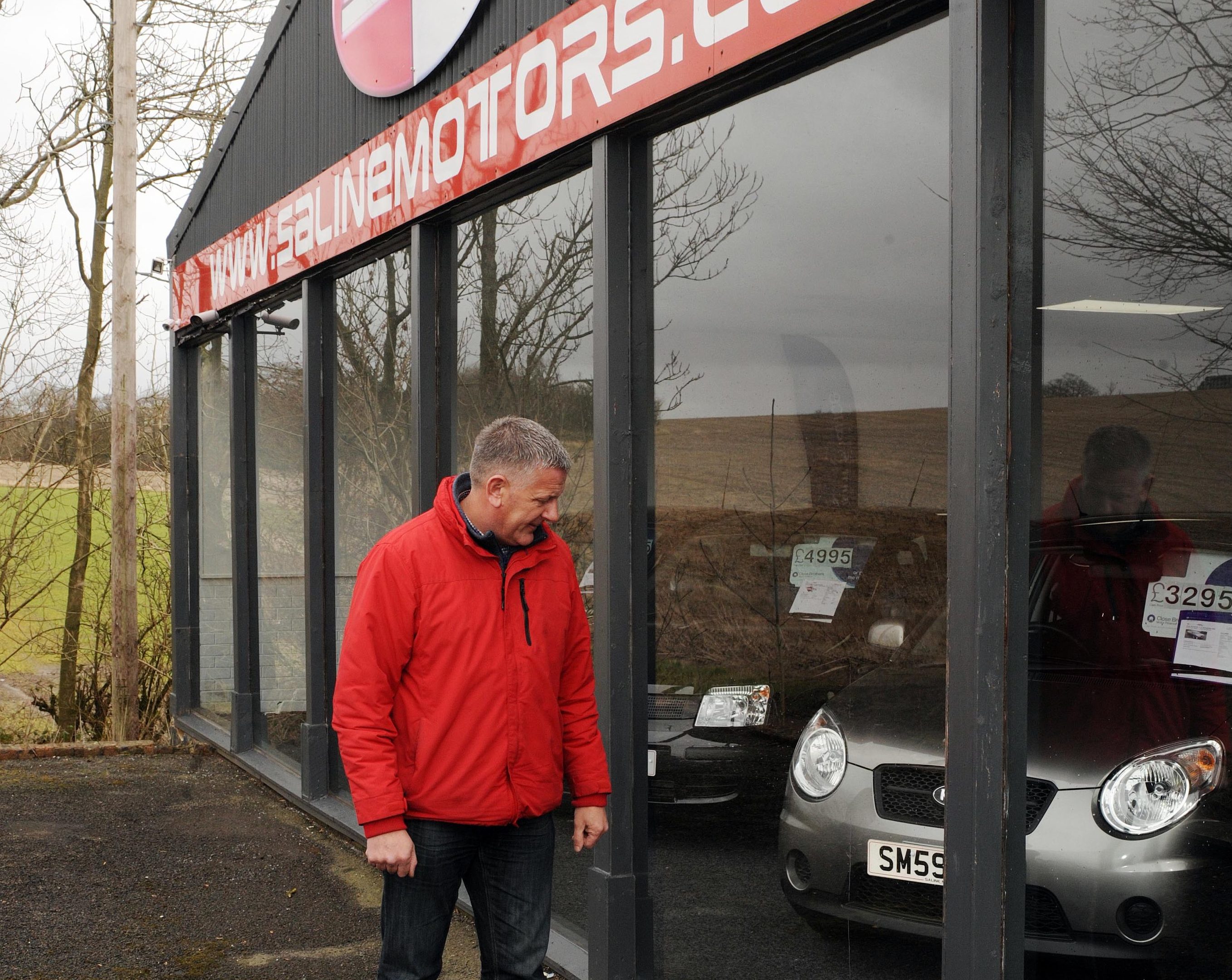 Owner Martin Blackadder inspects a damaged window at Saline Motors