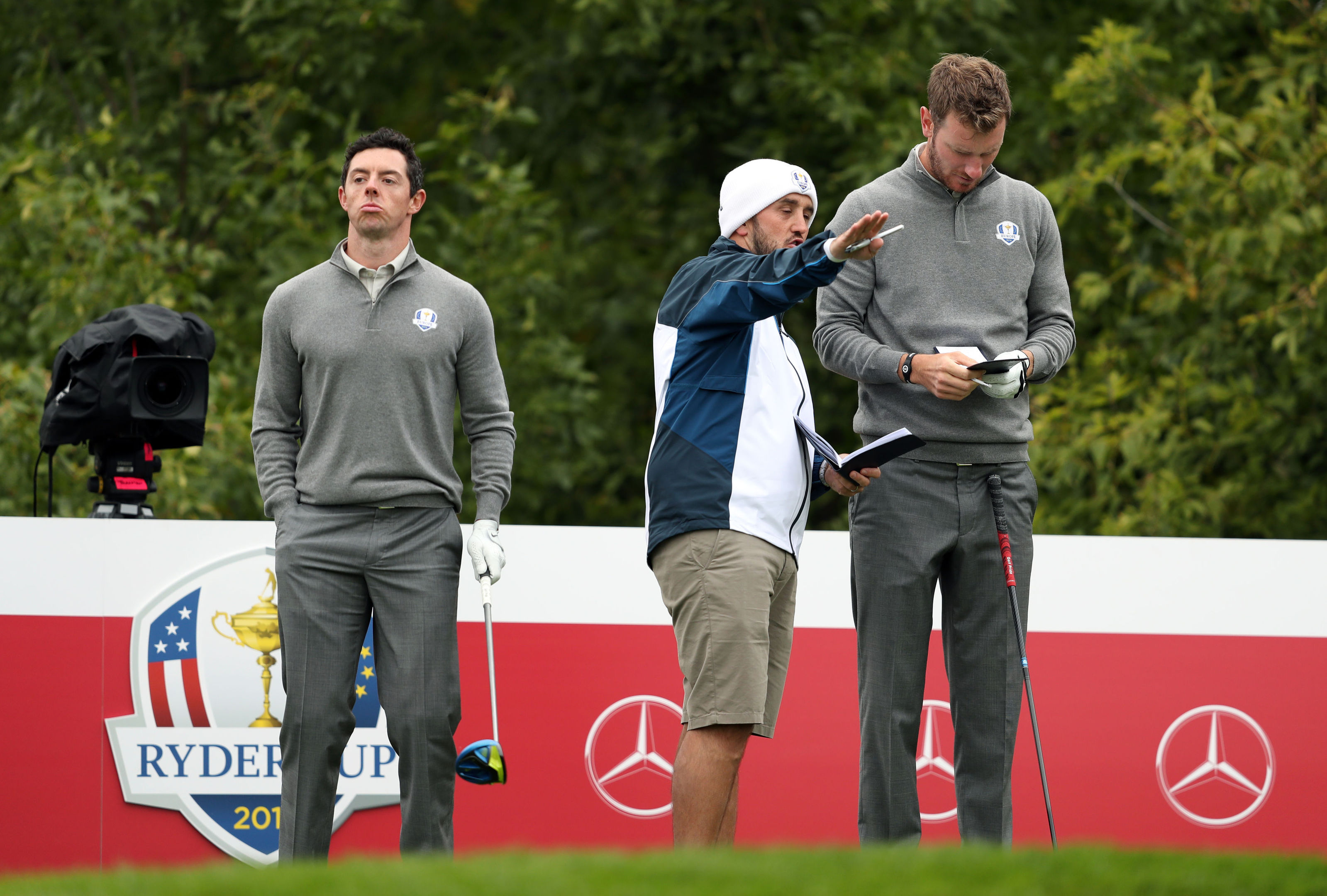 Chris Wood takes directions from Scottish caddie Mark Crane while Rory McIlroy waits during practice at Hazeltine.