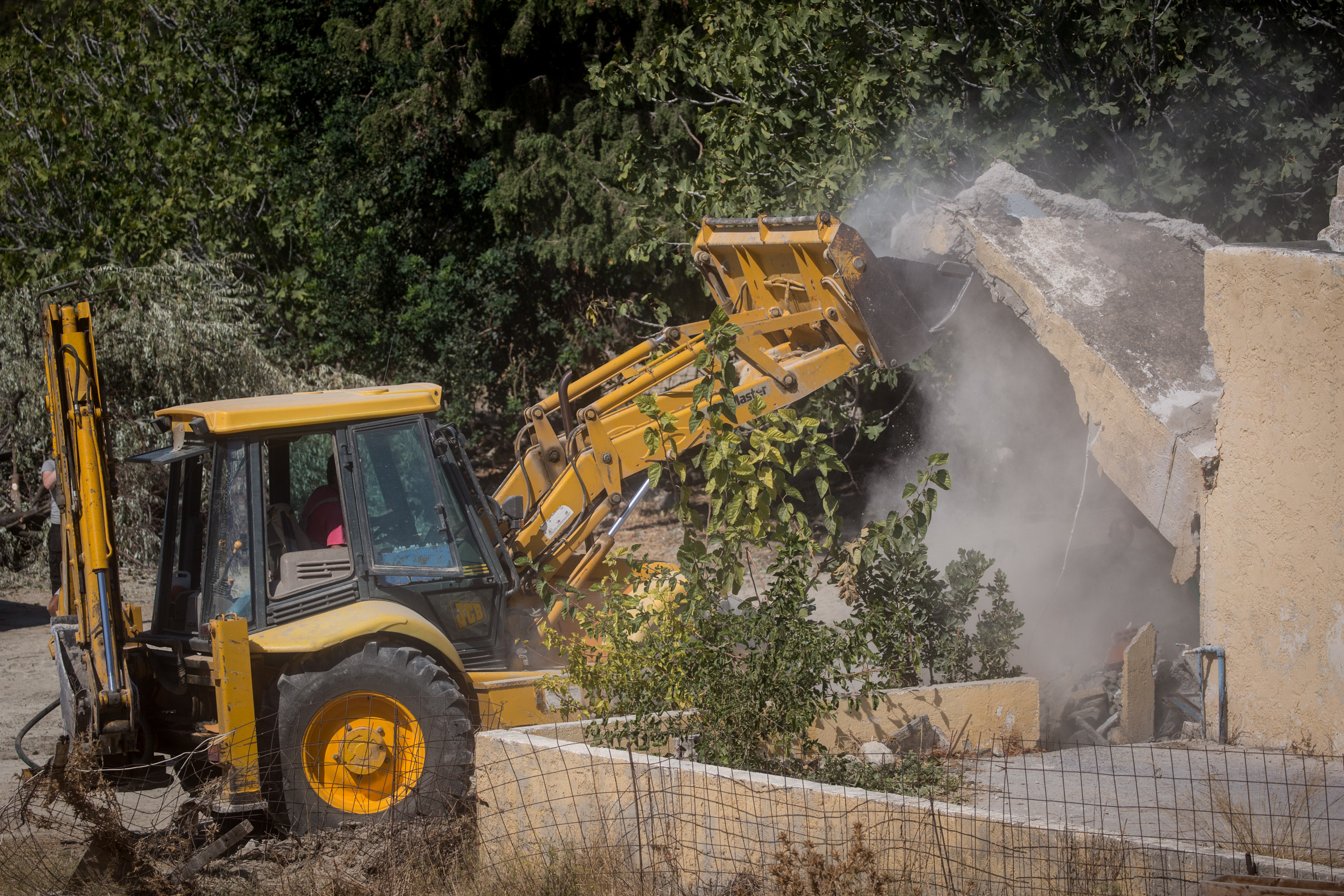 A bulldozer demolishes the last room of the farmhouse at the search site of missing toddler Ben Needham.